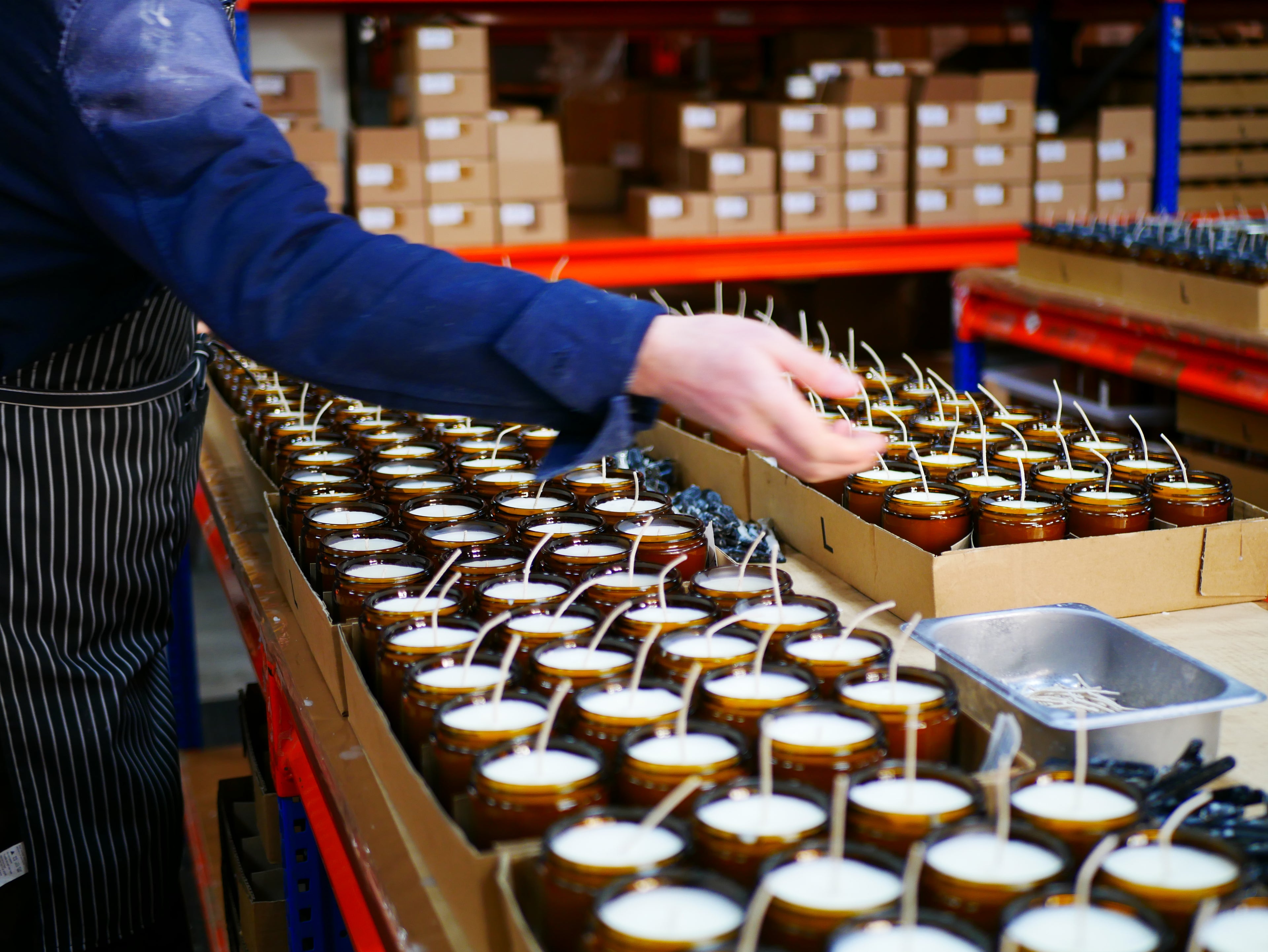 Person packaging candles into boxes in a warehouse setting